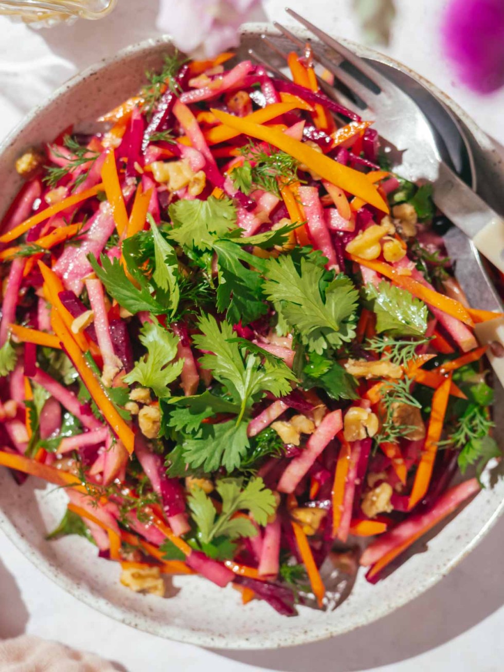 Beet and carrot salad on a plate with a fork and a knife.