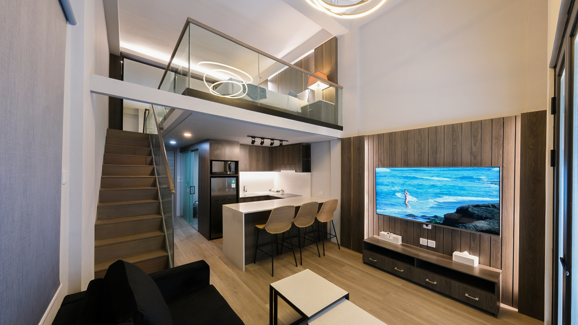 Living area and upper-level mezzanine bedroom in an Aster Apartment unit