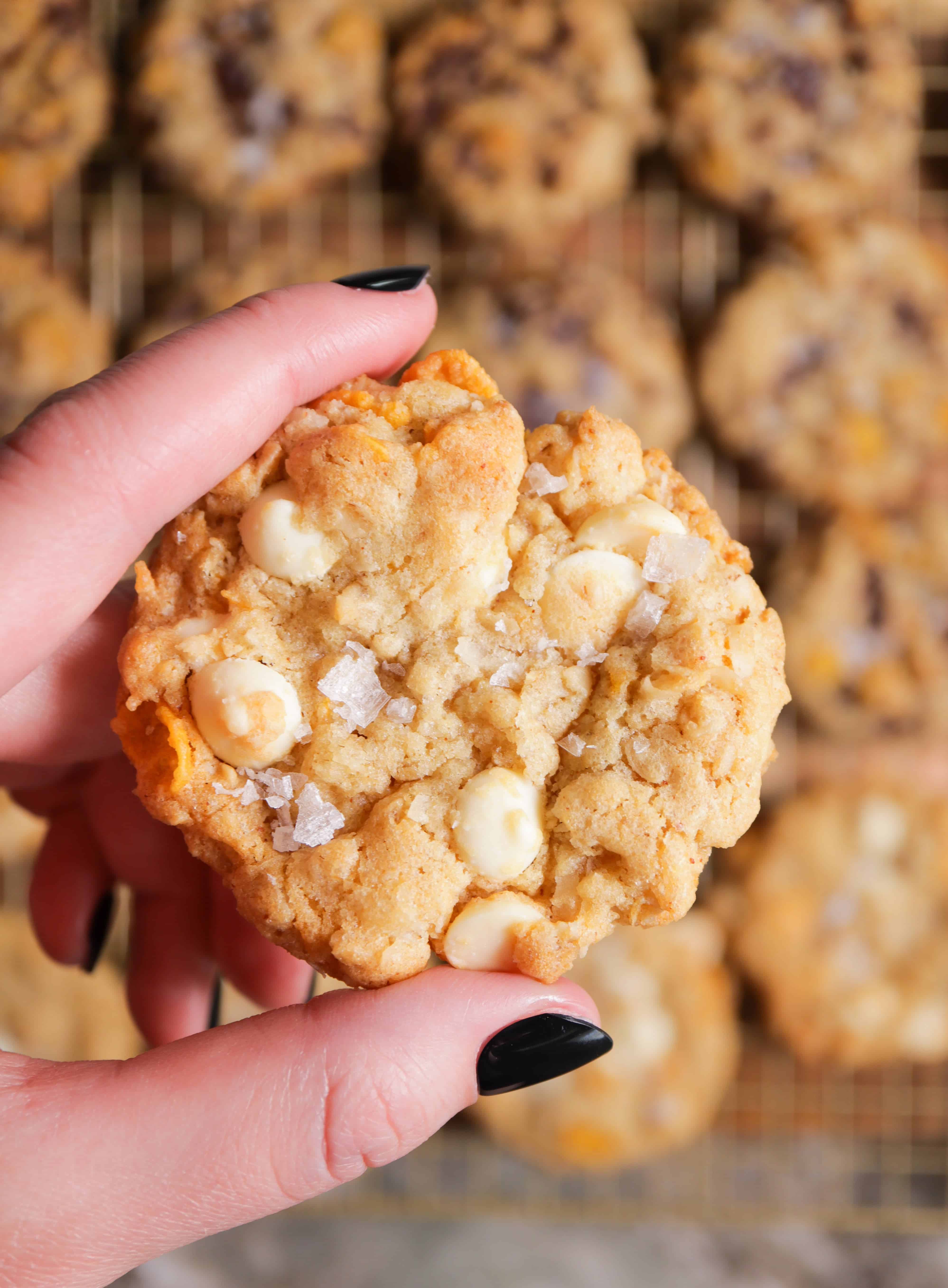 holding white chocolate ranger cookie above rack of all cookies