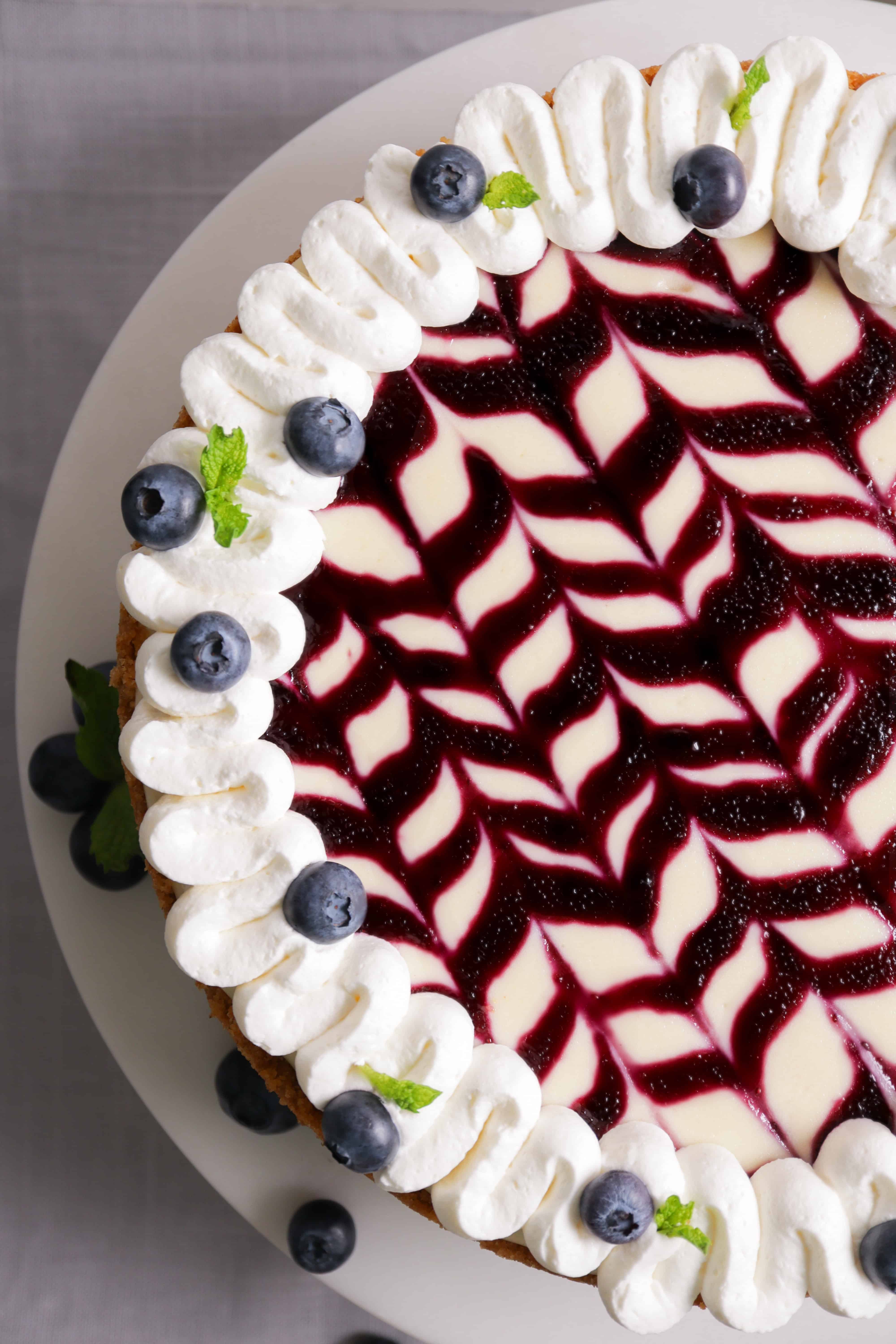 top view of line design in blueberry sauce on top of cheesecake with whipped cream rim