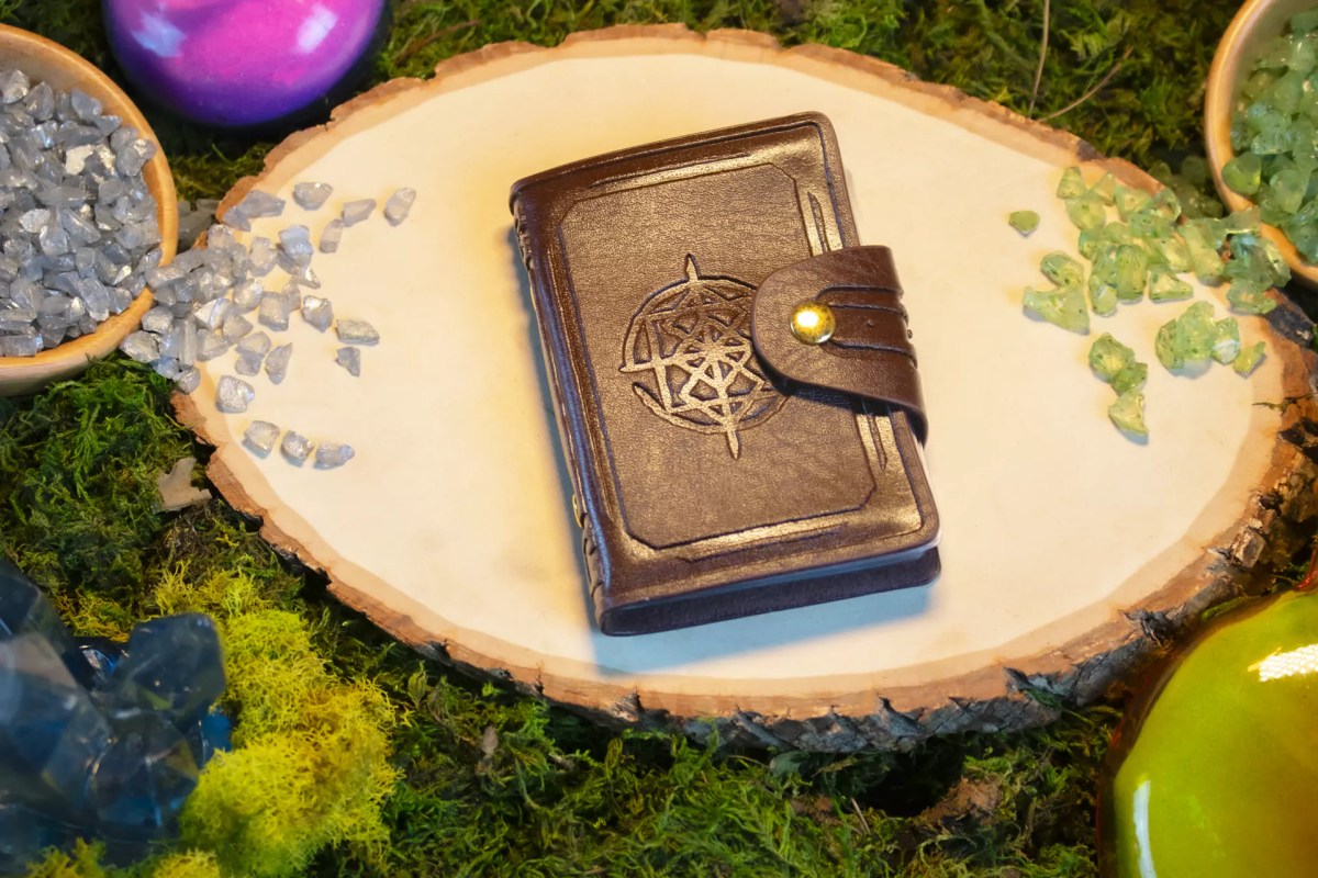 Zack Marsh Design, pocket compendium product photography of brown book on a wood round with fantasy props surrounding it
