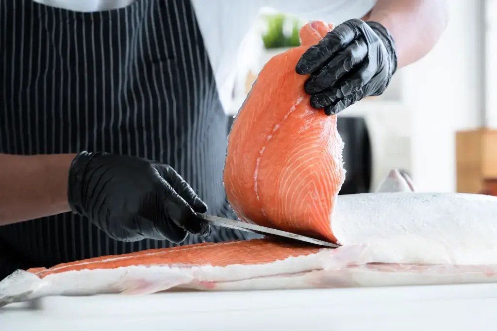 A chef cutting salmon with a Japanese knife.