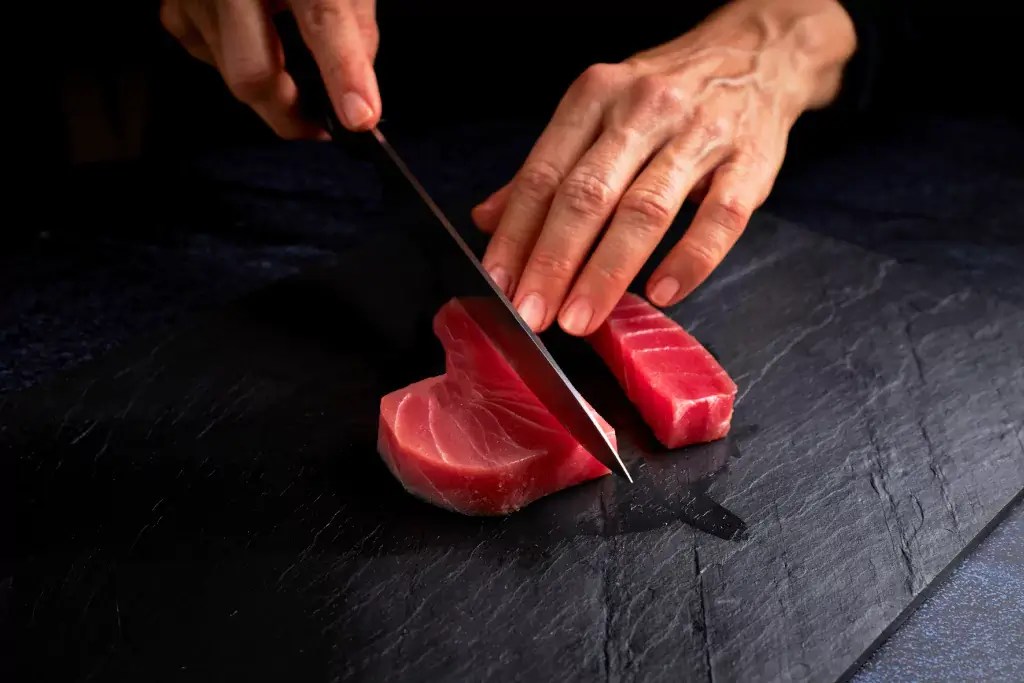 A person slicing raw tuna.