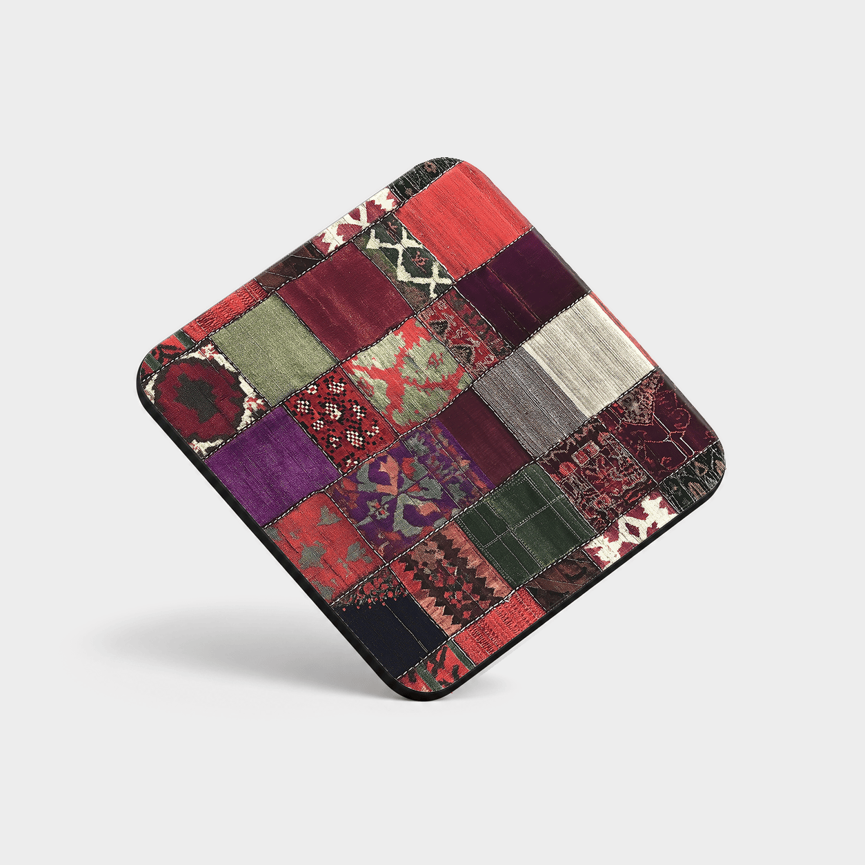 Fireside Patchwork Cork-Back Coaster with a grid of multicolored, rug-inspired printed blocks on a light gray background.