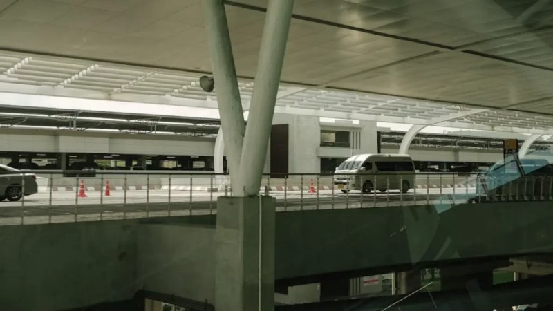 Vans e carros na área de embarque e desembarque de um aeroporto moderno.