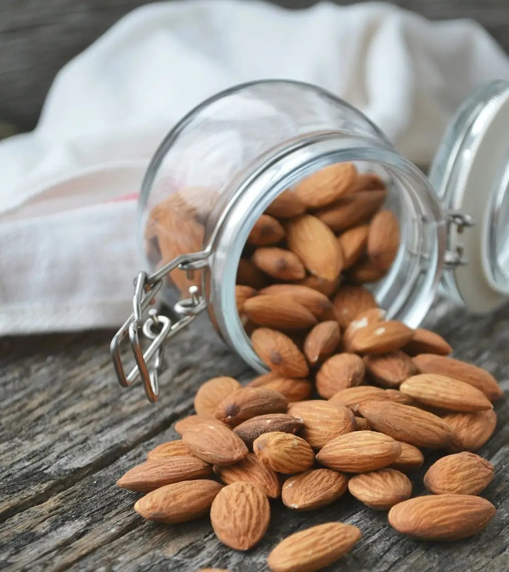 almonds falling out of a jar onto a grey wooden table