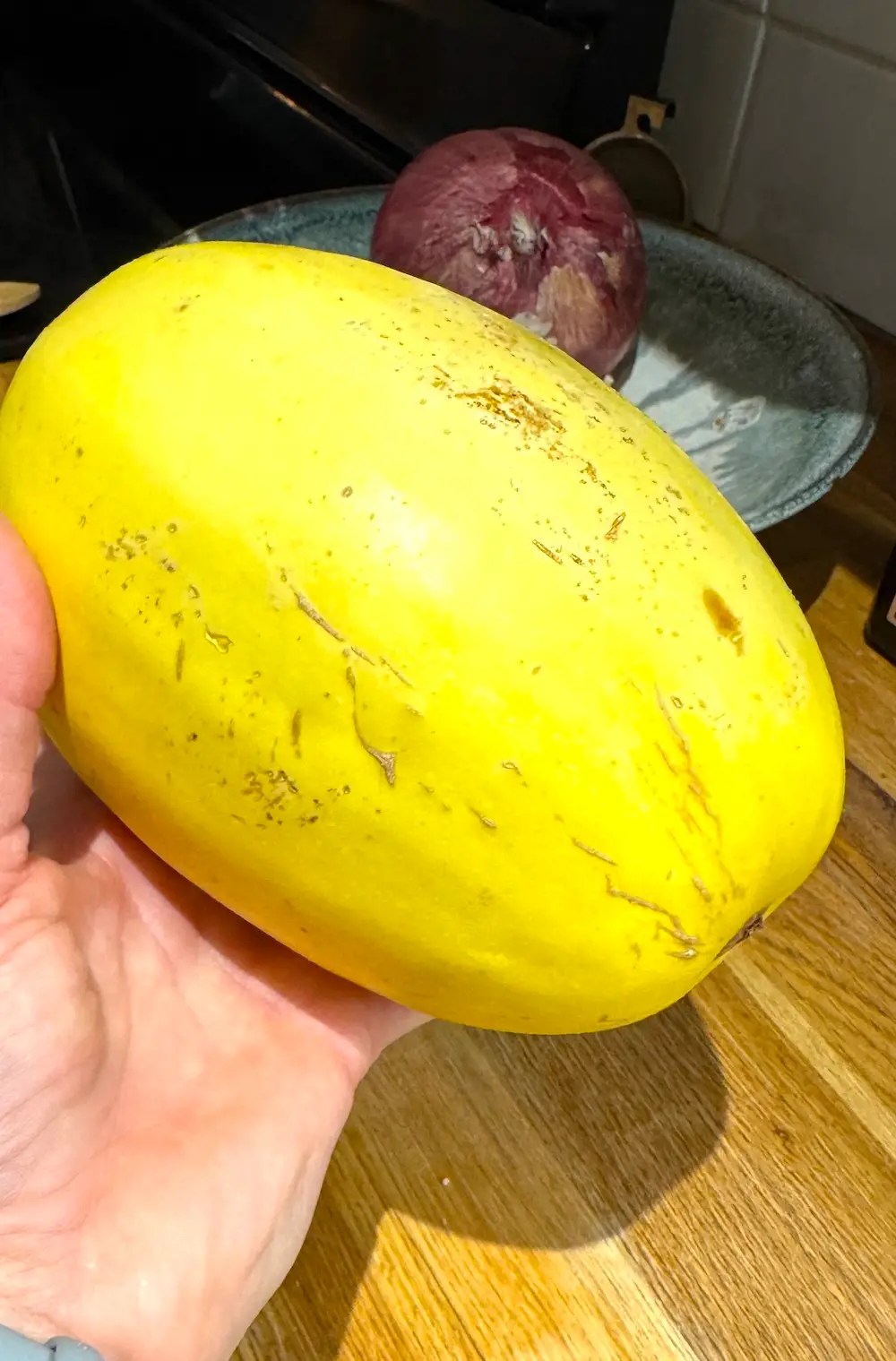 spaghetti squash in someone's hand getting ready to be cooked